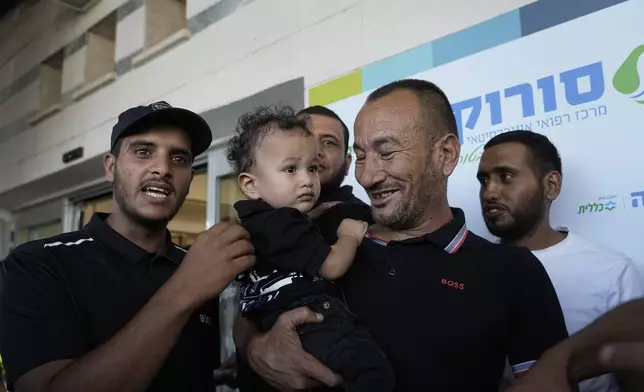 Ismail Al-Qadi, center, holds one of the sons of his brother, Kaid Farhan Al-Qadi, 52, who was held hostage by Hamas militants in the Gaza Strip, as they stand at the entrance of the Soroka Medical Center in Beersheba, Israel, Tuesday, Aug. 27, 2024. (AP Photo/Tsafrir Abayov)