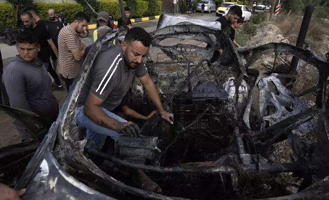 Palestinians inspect a car destroyed in a drone strike Zeita village, north of the West Bank city of Tulkarem, Saturday, Aug. 3, 2024. The Israeli military says it struck five suspected terrorists in a vehicle on their way to carry out an attack. (AP Photo/Majdi Mohammed)