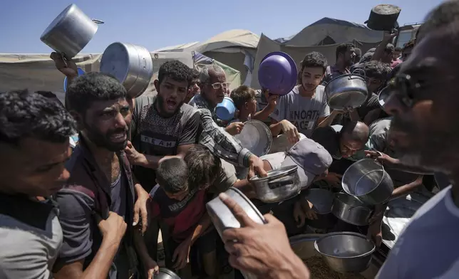 Displaced Palestinians gather at a food distribution center in Deir al Balah, central Gaza Strip, Friday, Aug. 23, 2024. (AP Photo/Abdel Kareem Hana)