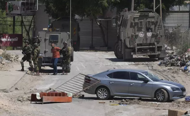 A Palestinian man is detained by members of the Israeli forces during a military operation in the West Bank refugee camp of Al-Faraa, Wednesday, Aug. 28, 2024. (AP Photo/Nasser Nasser)