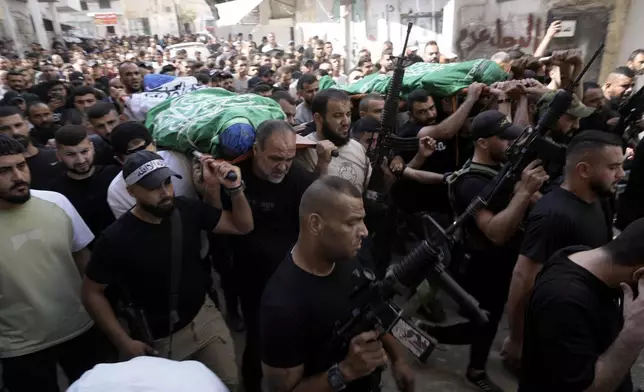 Mourners march during a funeral with the bodies of Palestinians Ahmed Abu Arra from the town of Aqaba, left, and Raafat Dawasa from the town of Silat Al-Harithiya, both draped in the Hamas flag and killed in an Israeli strike in the Jenin refugee camp, in the West Bank city of Jenin, Sunday, Aug. 18, 2024. Israel's military said Saturday it struck a "terrorist cell" in Jenin. The Palestinian health ministry there said two bodies were taken to a government hospital; Hamas claimed the two men as commanders in its military wing.(AP Photo/Majdi Mohammed)