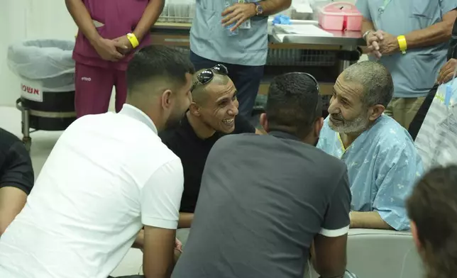 In this photo released by the Israel Prime Minister Office on Tuesday, Aug. 27, 2024, Kaid Farhan Al-Qadi, 52, right, who was held hostage by Hamas militants in Gaza sits in a room at the Soroka Medical Center in Beersheba, Israel. (Israel Prime Minister Office via AP)