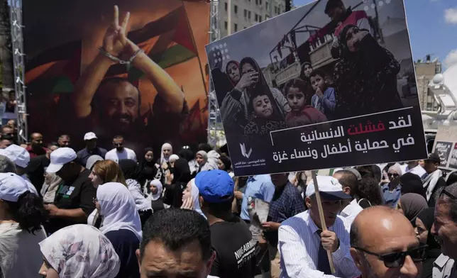 A protester carries a poster that reads "the humanity has failed in protecting the children and woman of Gaza," in front of a big poster of Marwan Barghouti, the highest profile Palestinian prisoner held by Israel, during a rally in solidarity with Gaza and prisoners held by Israel, in the West Bank city of Ramallah, Saturday, Aug. 3, 2024. (AP Photo/Nasser Nasser)