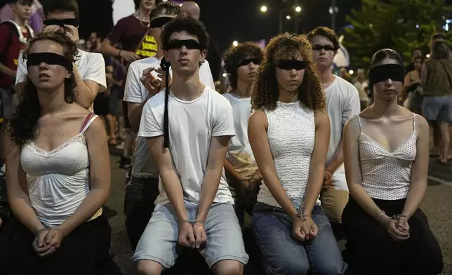 Relatives of hostages held by Hamas militants in the Gaza Strip and their supporters wear blindfolds to call for their immediate release and to protest against Israeli Prime Minister Benjamin Netanyahu's government in Tel Aviv, Israel, Saturday, Aug. 17, 2024. (AP Photo/Tsafrir Abayov)