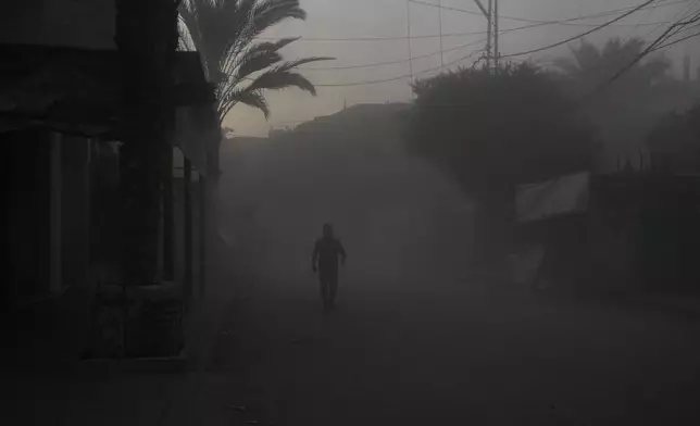 A Palestinian walks on a smoke-filled street after an Israeli airstrike in Deir al Balah, Gaza Strip, Tuesday, Aug. 6, 2024. (AP Photo/Abdel Kareem Hana)