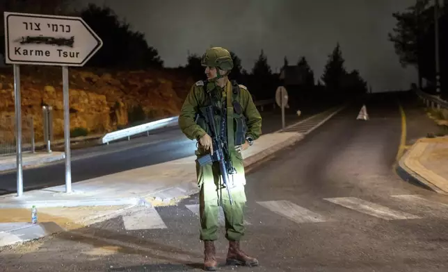 An Israeli soldier stands guard the near the scene of a car that exploded in the West Bank settlement of Karme Tsur, Saturday, Aug. 31, 2024. (AP Photo/Ohad Zwigenberg)