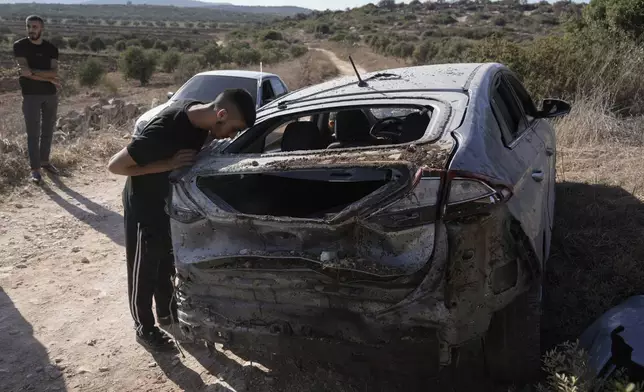 A Palestinian man looks inside a car damaged during a military operation near the West Bank refugee camp of Al-Faraa, Wednesday, Aug. 28, 2024. (AP Photo/Majdi Mohammed)