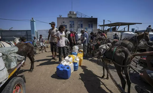 Displaced Palestinians line up to collect water, in Deir al Balah, central Gaza Strip, Friday, Aug. 23, 2024. (AP Photo/Abdel Kareem Hana)