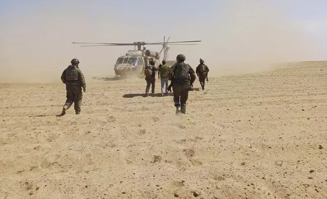 In this photo released by Israeli Defense Forces on Tuesday, Aug. 27, 2024, Israeli soldiers walk with Qaid Farhan Alkadi toward a military helicopter during the rescue operation. (Israeli Defense Forces via AP)