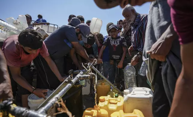 Displaced Palestinians line up to collect water, in Deir al Balah, central Gaza Strip, Friday, Aug. 23, 2024. (AP Photo/Abdel Kareem Hana)