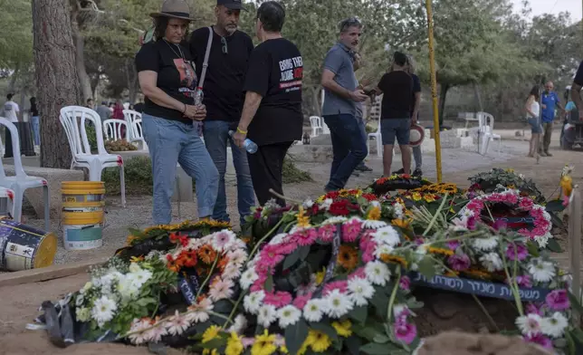 Keren Munder, the daughter of Avraham Munder, who was killed in Hamas captivity in the Gaza Strip and recovered by the Israeli military in Gaza, stands next to his grave at Kibbutz Nir Oz, southern Israel, Wednesday, Aug. 21, 2024. Her brother, Roee Munder, who was killed on Oct. 7, 2023, was reburied at the Kibbutz. (AP Photo/Ohad Zwigenberg)