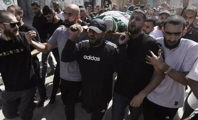 Mourners carry the body of militant Haitham Balidi, draped in the Qassam Brigade flag of the Hamas militant group's military wing, in Tulkarem refugee camp in the West Bank, Saturday, Aug. 3, 2024. He was killed in an Israeli drone strike, which Israeli military said struck five suspected terrorists in a vehicle on their way to carry out an attack. (AP Photo/Majdi Mohammed)