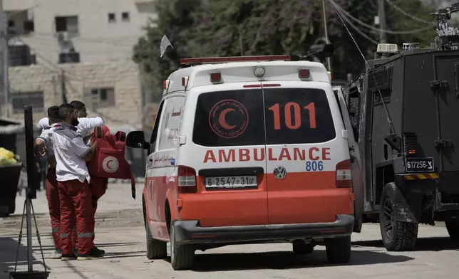 A Palestinian paramedic shows his bullet proof vest to the members of the Israeli forces inside an armoured vehicle during a military operation in the West Bank city of Jenin, Wednesday, Aug. 28, 2024. (AP Photo/Majdi Mohammed)