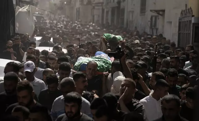 Mourners march during a funeral with the bodies of Palestinians Ahmed Abu Arra from the town of Aqaba, left, and Raafat Dawasa from the town of Silat Al-Harithiya, both draped in the Hamas flag and killed in an Israeli strike in the Jenin refugee camp, in the West Bank city of Jenin, Sunday, Aug. 18, 2024. Israel's military said Saturday it struck a "terrorist cell" in Jenin. The Palestinian health ministry there said two bodies were taken to a government hospital; Hamas claimed the two men as commanders in its military wing. (AP Photo/Majdi Mohammed)