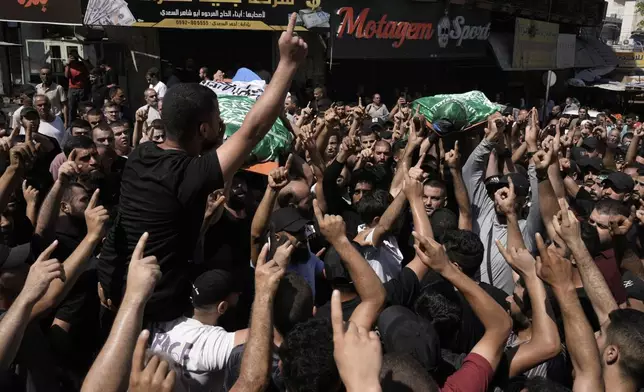 Mourners march during a funeral with the bodies of Palestinians Ahmed Abu Arra from the town of Aqaba, left, and Raafat Dawasa from the town of Silat Al-Harithiya, both draped in the Hamas flag and killed in an Israeli strike in the Jenin refugee camp, in the West Bank city of Jenin, Sunday, Aug. 18, 2024. Israel's military said Saturday it struck a "terrorist cell" in Jenin. The Palestinian health ministry there said two bodies were taken to a government hospital; Hamas claimed the two men as commanders in its military wing. (AP Photo/Majdi Mohammed)