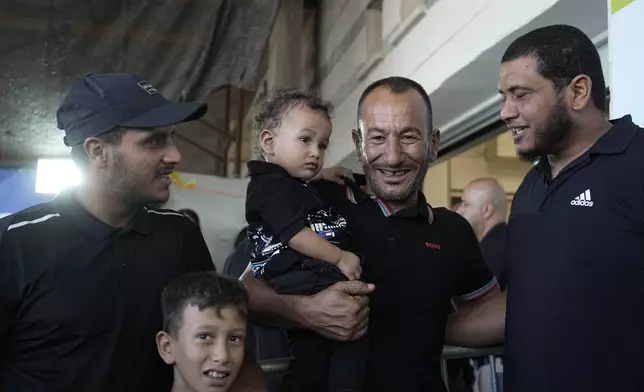 Ismail Al-Qadi, center, holds one of the sons of his brother, Kaid Farhan Al-Qadi, 52, who was held hostage by Hamas militants in the Gaza Strip, as he stand next to his other two nephews and a relative, at the entrance of the Soroka Medical Center in Beersheba, Israel, Tuesday, Aug. 27, 2024. (AP Photo/Tsafrir Abayov)