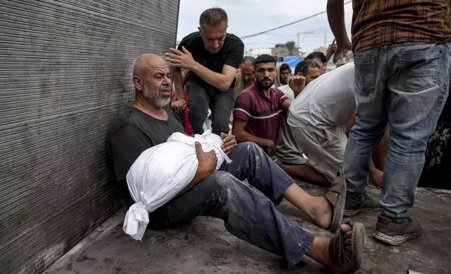 A Palestinian man holds the body of a relative killed in the Israeli bombardment of the Gaza Strip, at a hospital in Deir al-Balah, Thursday, Aug. 22, 2024. (AP Photo/Abdel Kareem Hana)