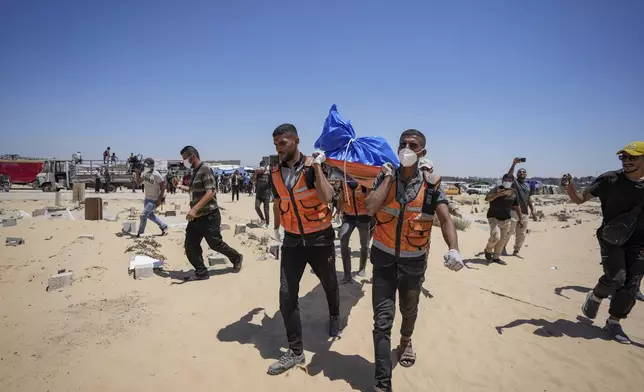 Workers carry a body returned by Israel to a cemetery in Khan Younis, Gaza Strip, Monday, Aug. 5, 2024. A Palestinian official says Israel has returned more than 80 bodies to the Gaza Strip. The identities of the deceased and the cause of death were not immediately known. (AP Photo/Abdel Kareem Hana)