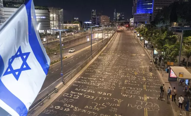 Names of the hostages held in the Gaza Strip by Hamas militants are written in Hebrew on a road in Tel Aviv, Tuesday, Aug. 27, 2024 . (AP Photo/Ohad Zwigenberg)