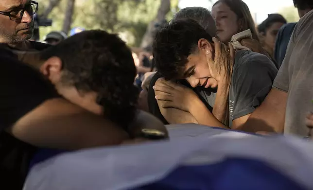 Family members mourn over the coffin of Yoram Metzger during his funeral at a cemetery of the kibbutz Nir Oz, southern Israel, Thursday, Aug. 22, 2024. Metzger's body was one the six bodies of hostages, taken in Hamas' Oct. 7 attack, recovered by Israel's military during an operation in the Gaza Strip. (AP Photo/Tsafrir Abayov)