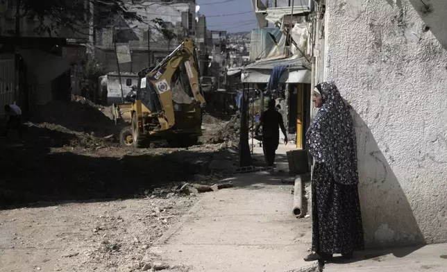 A Palestinian woman watches an operation by the Israeli military in Tulkarem refugee camp in the West Bank, Saturday, Aug. 3, 2024. The Israeli military said it struck five suspected terrorists in a vehicle on their way to carry out an attack. (AP Photo/Majdi Mohammed)