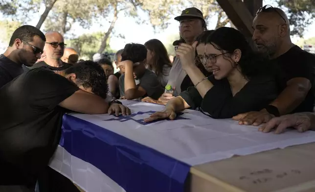 Family members mourn over the coffin of Yoram Metzger during his funeral at a cemetery of the kibbutz Nir Oz, southern Israel, Thursday, Aug. 22, 2024. Metzger's body was one the six bodies of hostages, taken in Hamas' Oct. 7 attack, recovered by Israel's military during an operation in the Gaza Strip. (AP Photo/Tsafrir Abayov)