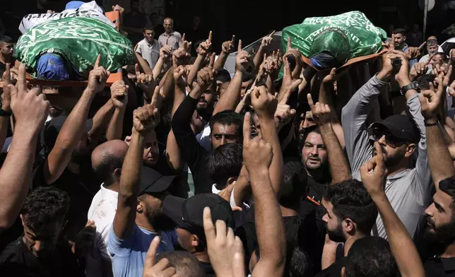 Mourners march during a funeral with the bodies of Palestinians Ahmed Abu Arra from the town of Aqaba, left, and Raafat Dawasa from the town of Silat Al-Harithiya, both draped in the Hamas flag and killed in an Israeli strike in the Jenin refugee camp, in the West Bank city of Jenin, Sunday, Aug. 18, 2024. Israel's military said Saturday it struck a "terrorist cell" in Jenin. The Palestinian health ministry there said two bodies were taken to a government hospital; Hamas claimed the two men as commanders in its military wing. (AP Photo/Majdi Mohammed)