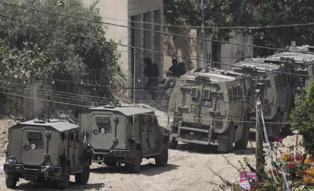 Member of the Israeli forces take position next to the armoured vehicles during a military operation in the West Bank Jenin refugee camp, Saturday, Aug. 31, 2024. (AP Photo/Majdi Mohammed)