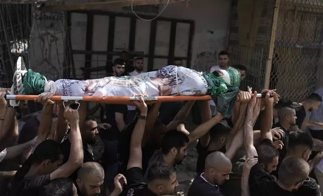 Mourners carry the body of militant Haitham Balidi, draped in the Qassam Brigade flag of the Hamas militant group's military wing, in Tulkarem refugee camp in the West Bank, Saturday, Aug. 3, 2024. He was killed in an Israeli drone strike, which Israeli military said struck five suspected terrorists in a vehicle on their way to carry out an attack. (AP Photo/Majdi Mohammed)