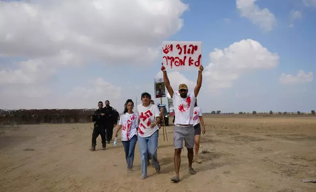 Relatives and friends of hostages held in the Gaza Strip by the Hamas militant group take part in a protest calling for their release as they walk on an area outside the kibbutz Nirim, southern Israel, Thursday, Aug. 29, 2024. (AP Photo/Tsafrir Abayov)