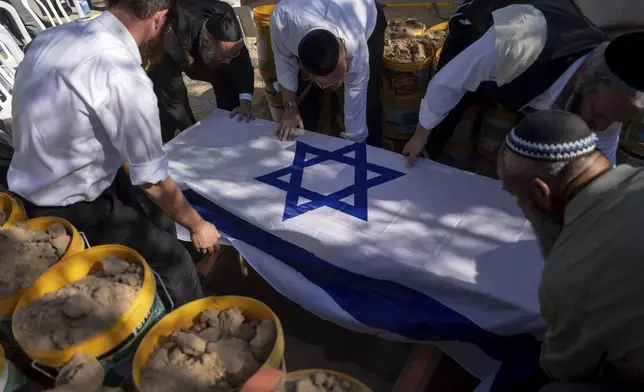 Workers from "Hevra Kadisha" lower the coffin of Avraham Munder, who was killed in Hamas captivity in the Gaza Strip and recovered by the Israeli military in Gaza, during his funeral at a cemetery of the Kibbutz Nir Oz southern Israel, Wednesday, Aug. 21, 2024. On Tuesday, the Israeli military said its forces recovered six bodies of hostages kidnapped on Oct. 7 in an overnight operation in southern Gaza. (AP Photo/Ohad Zwigenberg)