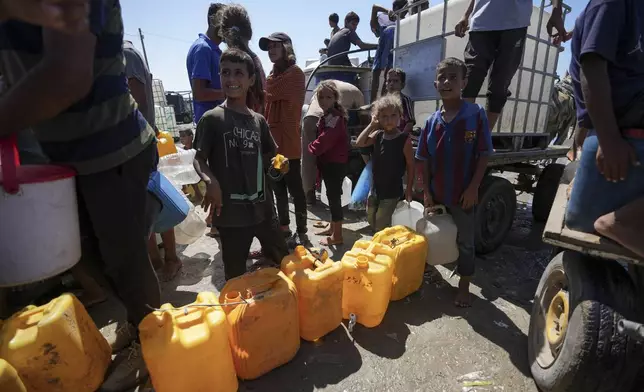 Displaced Palestinians line up to collect water, in Deir al Balah, central Gaza Strip, Friday, Aug. 23, 2024. (AP Photo/Abdel Kareem Hana)