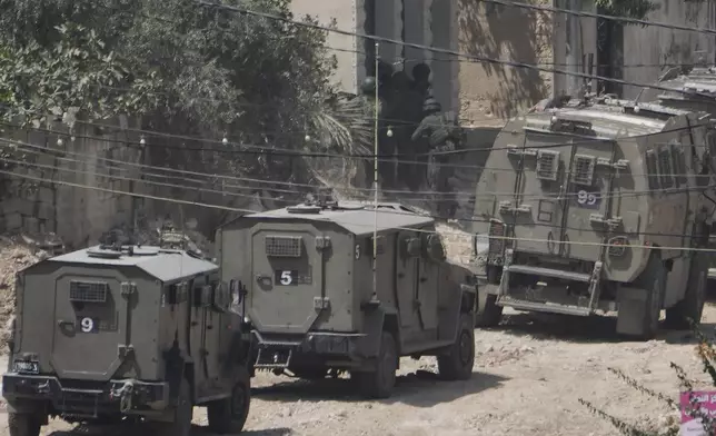 Member of the Israeli forces take position next to the armoured vehicles during a military operation in the West Bank Jenin refugee camp, Saturday, Aug. 31, 2024. (AP Photo/Majdi Mohammed)