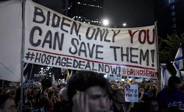 Activists carry a message for U.S. President Joe Biden as relatives of hostages held by Hamas militants in the Gaza Strip and their supporters call for their immediate release and to protest against Israeli Prime Minister Benjamin Netanyahu's government in Tel Aviv, Israel, Saturday, Aug. 24, 2024. (AP Photo/Maya Alleruzzo)