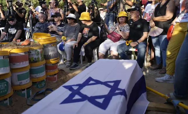 Mourners wait for the funeral for slain hostage Avraham Munder, who was killed in Hamas captivity in the Gaza Strip, at Kibbutz Nir Oz, southern Israel, Wednesday, Aug. 21, 2024. His son, Roee, who was killed on Oct. 7, 2023, was reburied at the Kibbutz. On Tuesday, the Israeli military said its forces recovered six bodies of hostages kidnapped on Oct. 7, 2023 in an overnight operation in southern Gaza.(AP Photo/Ohad Zwigenberg)