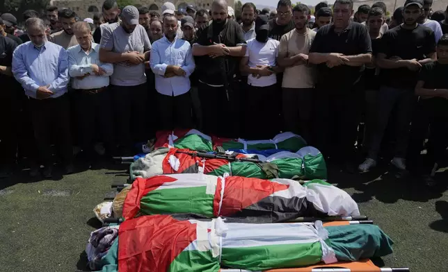 Mourners pray as they attend the funeral of four Palestinians, wrapped in Palestinian flags, who died during an Israeli military operation in the West Bank refugee camp of Al-Faraa, near Tubas, Thursday, Aug. 29, 2024. (AP Photo/Nasser Nasser)