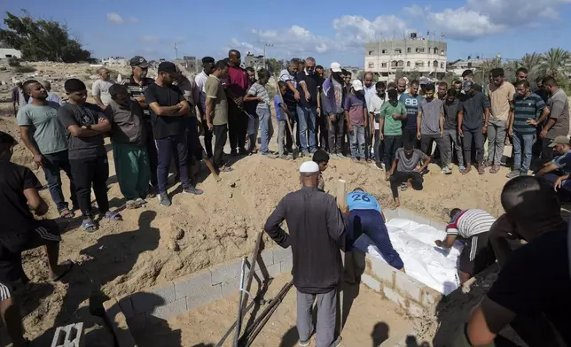 Palestinian grave digger Sa'di Baraka, center, oversees a burial in the cemetery in Deir al-Balah, Gaza Strip, Saturday, Aug. 10, 2024. (AP Photo/Abdel Kareem Hana)