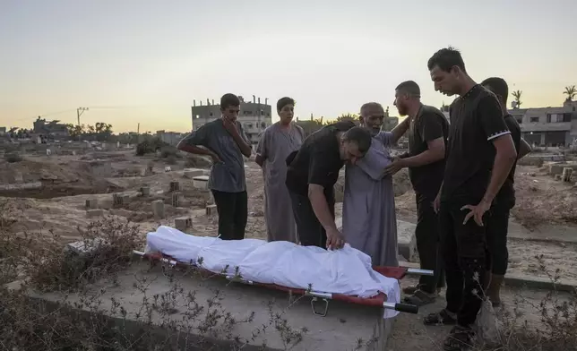 Palestinian mourners prepare to bury their loved one at the cemetery in Deir al-Balah, Gaza Strip, Friday, Aug. 9, 2024. (AP Photo/Abdel Kareem Hana)