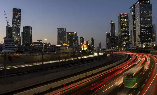 In this photo with a long exposure, traffic moves slowly in Tel Aviv, Israel, Wednesday, Aug. 14, 2024. Israel's economy is suffering from the nearly 11-month war with Hamas, as its leaders grind ahead with its offensive in Gaza that threatens to escalate into a wider conflict. (AP Photo/Ariel Schalit)