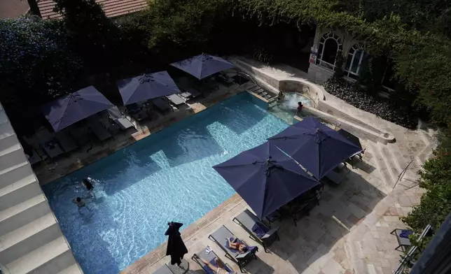 Guests swim and sunbathe at the pool at the American Colony Hotel in east Jerusalem, Sunday, Aug. 18, 2024. As Israel’s economy is suffering from the nearly 11-month war with Hamas, Jerusalem’s iconic American Colony hotel has had to lay off workers and are mulling pay cuts, said Jeremy Berkovitz, the official representative of the owners. (AP Photo/Mahmoud Illean)