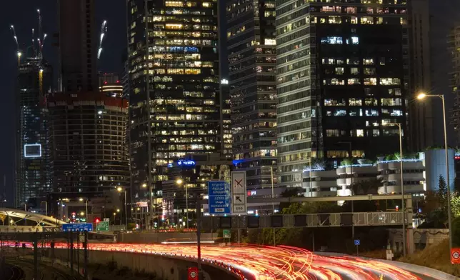 In this photo taken with a long exposure, traffic moves slowly in Tel Aviv, Israel, Wednesday, Aug. 14, 2024. Israel's economy is suffering from the nearly 11-month war with Hamas, as its leaders grind ahead with its offensive in Gaza that threatens to escalate into a wider conflict. (AP Photo/Ariel Schalit)