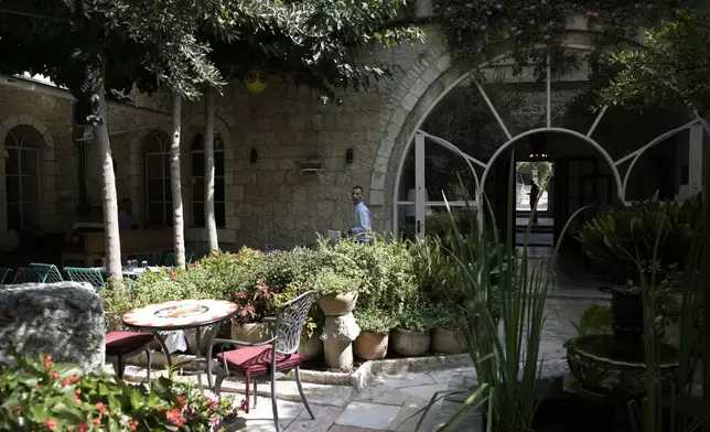 A worker walks through the garden courtyard where breakfast is served American Colony Hotel in east Jerusalem, Sunday, Aug. 18, 2024. As Israel’s economy is suffering from the nearly 11-month war with Hamas, Jerusalem’s iconic American Colony hotel has had to lay off workers and are mulling pay cuts, said Jeremy Berkovitz, the official representative of the owners. (AP Photo/Mahmoud Illean)