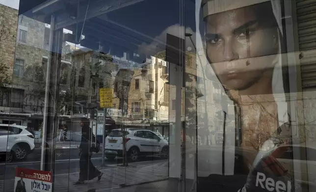 A woman walks past a closed shop in Haifa, Israel, Thursday, Aug. 15, 2024. (AP Photo/Leo Correa)