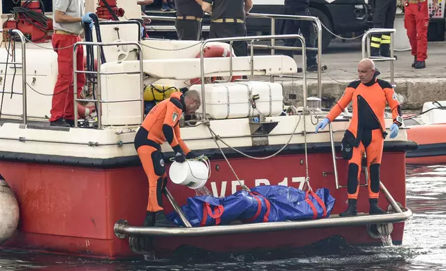 Italian firefighter divers bring ashore in a plastic bag the body of one of the victims of a shipwreck, in Porticello, Sicily, southern Italy, Thursday, Aug. 22, 2024. Divers searching the wreck of the superyacht Bayesian that sank off Sicily on Monday recovered a fifth body on Thursday and continued to search for one more as investigators sought to learn why the vessel sank so quickly. (AP Photo/Salvatore Cavalli)