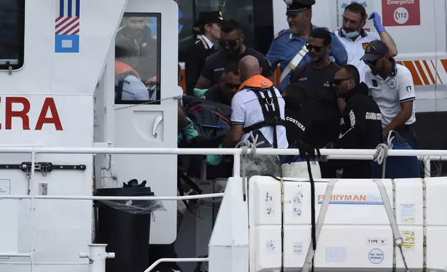 Italian Firefighters scuba divers bring ashore in a bag the body of one of the victims of the UK flag vessel Bayesian, Wednesday, Aug. 21, 2024. The sail yacht was hit by a violent sudden storm and sunk early Monday, while at anchor off the Sicilian village of Porticello near Palermo, in southern Italy. (AP Photo/Salvatore Cavalli)