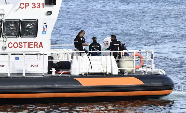 Italian Coast Guard officials bring ashore in a bag the body of one of the victims of the UK flag vessel Bayesian, Wednesday, Aug. 21, 2024. The sail yacht was hit by a violent sudden storm and sunk early Monday, while at anchor off the Sicilian village of Porticello near Palermo, in southern Italy. (AP Photo/Salvatore Cavalli)