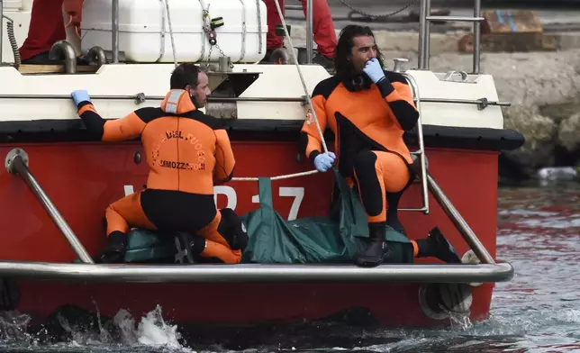 Italian Firefighters scuba divers return to the harbor with a body bag, Wednesday, Aug. 21, 2024, in the Sicilian village of Porticello near Palermo, in southern Italy. (AP Photo/Salvatore Cavalli