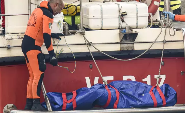 Italian firefighter divers bring ashore in a plastic bag the body of one of the victims of a shipwreck, in Porticello, Sicily, southern Italy, Thursday, Aug. 22, 2024. Divers searching the wreck of the superyacht Bayesian that sank off Sicily on Monday recovered a fifth body on Thursday and continued to search for one more as investigators sought to learn why the vessel sank so quickly. (AP Photo/Salvatore Cavalli)