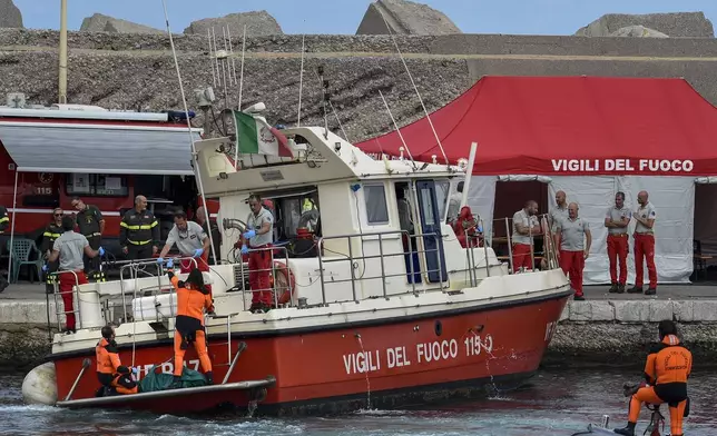 Italian firefighter divers bring ashore in a green bag the body of one of the victims of the UK flag vessel Bayesian, Wednesday, Aug. 21, 2024. The luxury sail yacht was hit by a violent sudden storm and sunk early Monday, while at anchor off the Sicilian village of Porticello near Palermo, in southern Italy. (AP Photo/Salvatore Cavalli)