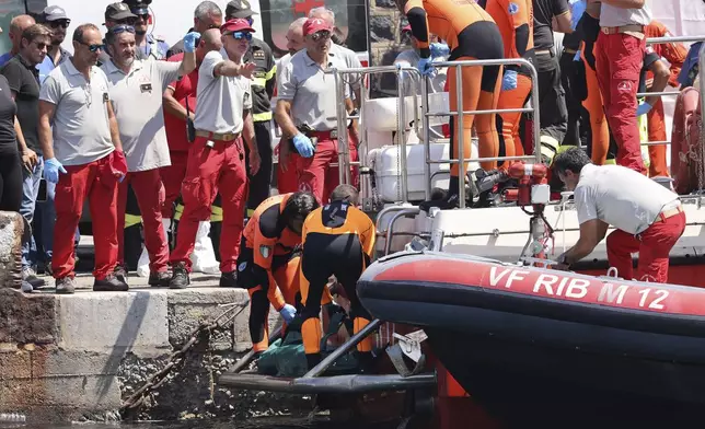 Italian firefighter divers bring ashore in a plastic bag the body of one of the victims of a shipwreck, in Porticello, Sicily, southern Italy, Friday Aug. 23, 2024. Italian rescuers brought ashore the body of the final missing person who was on a superyacht that sunk off the coast of Sicily. (Alberto Lo Bianco/LaPresse via AP)